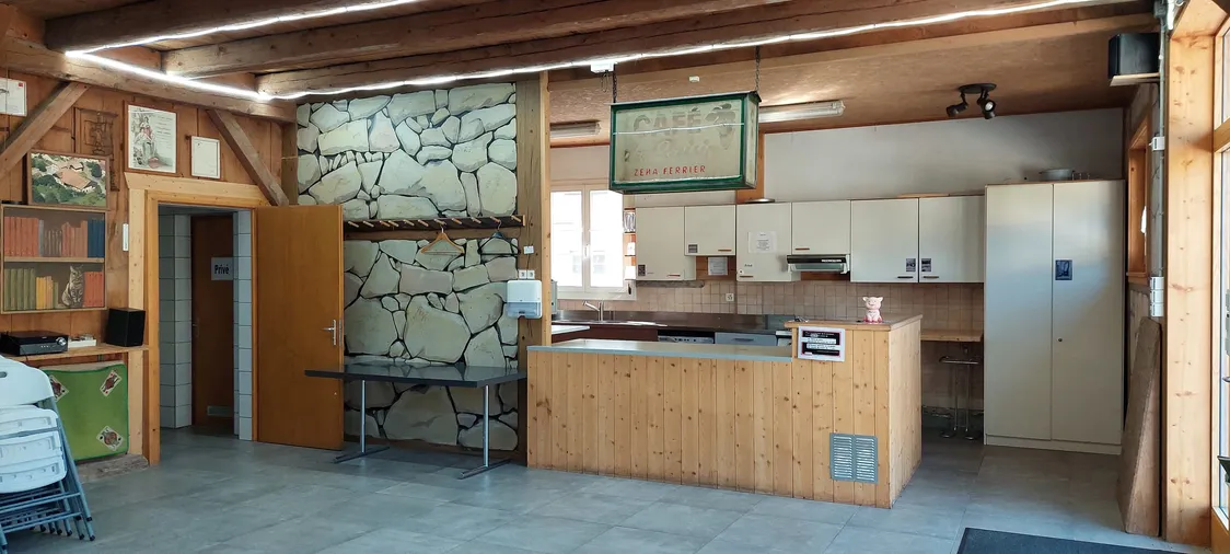 Le bar en bois et son mur en pierres apparentes, sous l’enseigne d’époque « Café du Raisin »