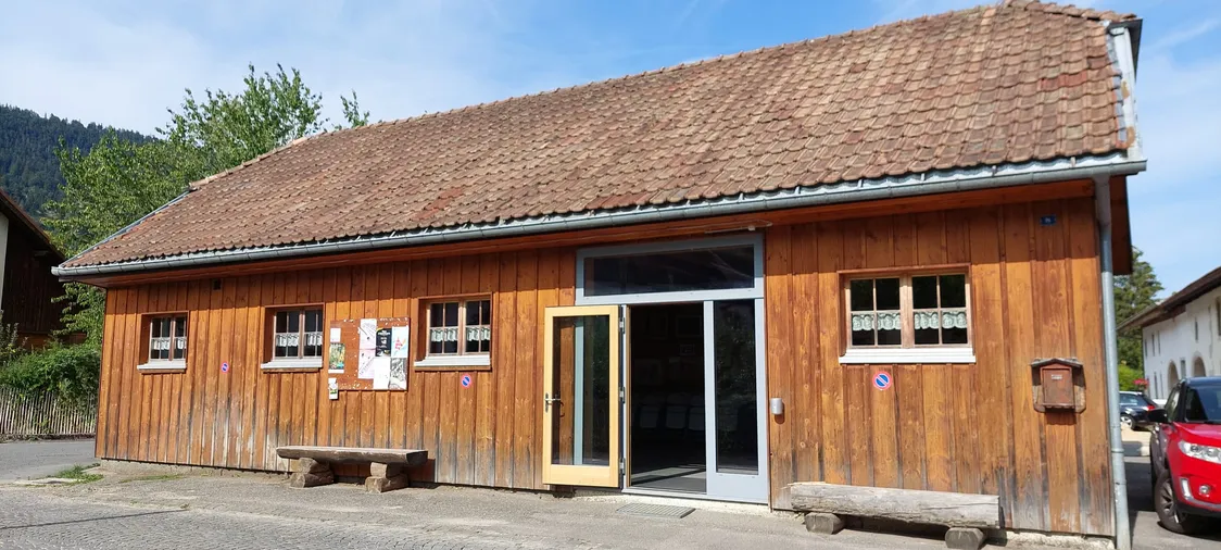 L'entrée vitrée grande ouverte, encadrée par ses bancs en bois massif