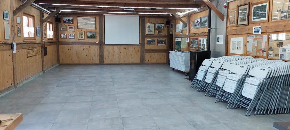 La salle vide vers l'écran de projection, chaises pliantes et tables rangées sur le côté