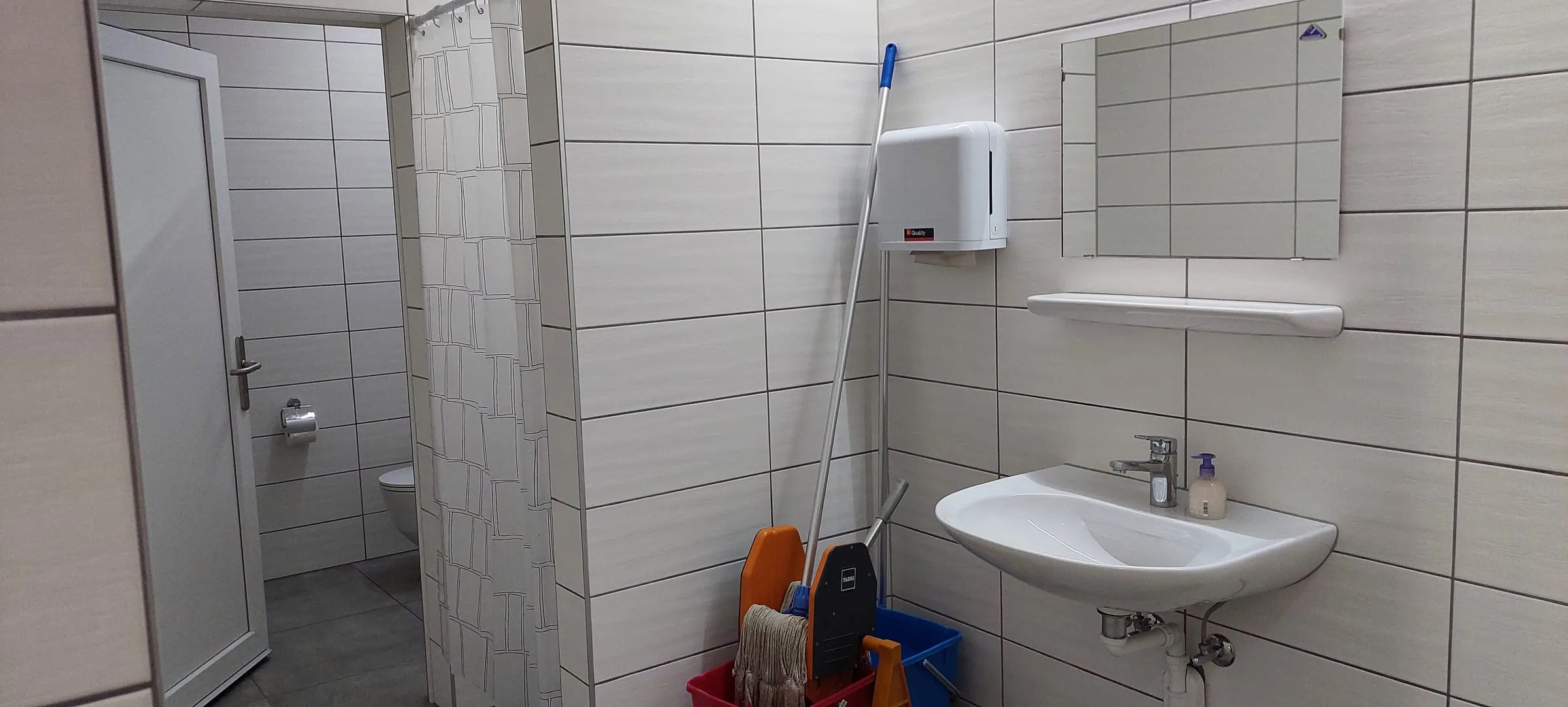 Les sanitaires entièrement carrelés : lavabo, miroir, distributeur et WC séparés