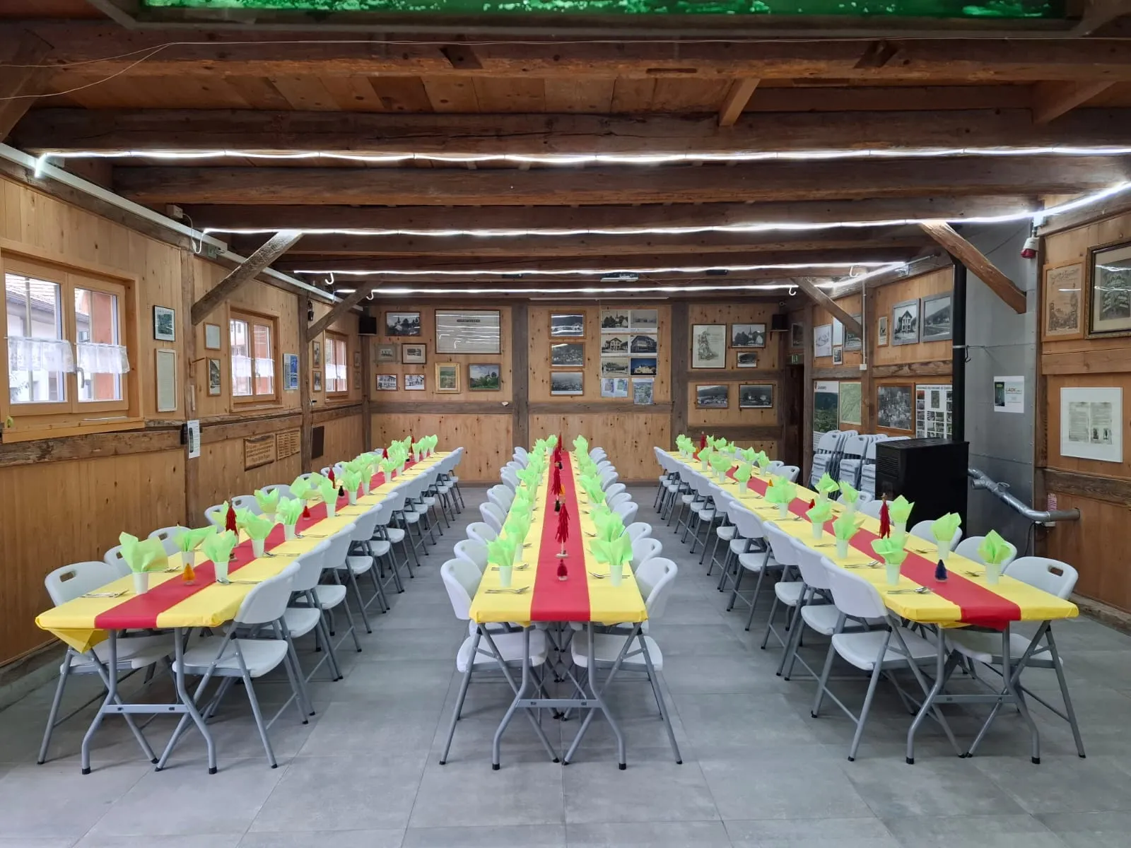 La grande salle dressée en banquet, nappes jaune et rouge et couverts en place